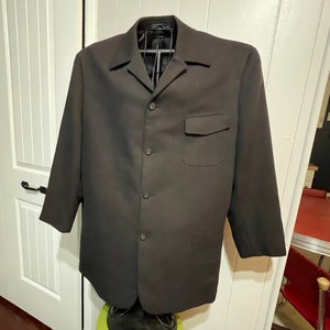 May include: A black blazer with a button-up front and a single pocket on the left side. The blazer has a collar and long sleeves.