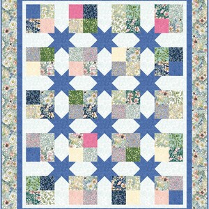 May include: A quilt with a white background and a blue border. The quilt is made up of smaller squares of different floral patterns in shades of pink, blue, green, and cream. The squares are arranged in a grid pattern, and the quilt is stitched together with blue thread.