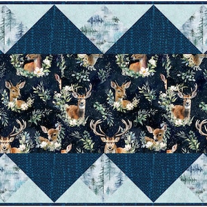 May include: A decorative quilt with a central panel showcasing deer and floral patterns on a dark backdrop. The design is framed by blue geometric shapes and a light blue border, creating a rustic, woodland theme.
