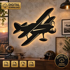 May include: A black silhouette of a biplane wall art piece with a glowing backlight. The design features a vintage aircraft with two stacked wings and a propeller. This is a digital download file available in SVG, DXF, AI, and CDR formats.