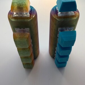 May include: Two vertical cylindrical macro keypads with a rainbow gradient finish. The left keypad features translucent yellow-green keycaps, while the right keypad has solid blue keycaps. Both devices have white mechanical switches visible beneath the keys.