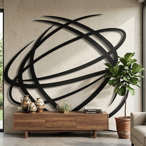 May include: A large black metal wall sculpture featuring intersecting curved lines and circular loops. The piece is mounted on a textured light-colored wall above a wooden media console that holds three ceramic vases and a stack of books.