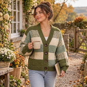 May include: A long-sleeve crochet cardigan featuring a patchwork pattern of sage green, olive green, and cream-coloured squares. The garment has a V-neckline, a ribbed front placket with four dark brown buttons, and ribbed cuffs and hem.