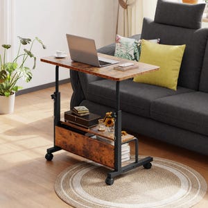 May include: A mobile laptop desk with a brown wood-grain surface and a black metal frame. The desk features an adjustable height mechanism, a lower storage shelf, and a vertical side panel. It is equipped with four caster wheels for mobility.