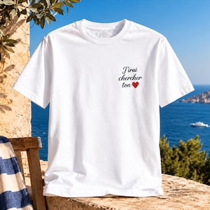 Op de afbeelding: Een wit t-shirt met korte mouwen en de zwarte tekst J'irai chercher ton gevolgd door een klein rood hartje op de linkerborst. Het kledingstuk heeft een klassieke ronde hals en een standaard pasvorm met korte mouwen.