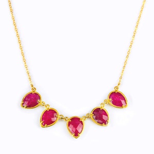 Op de afbeelding: Een gouden ketting met vijf druppelvormige robijnen.