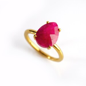 May include: A gold ring with a large, faceted, pink gemstone.