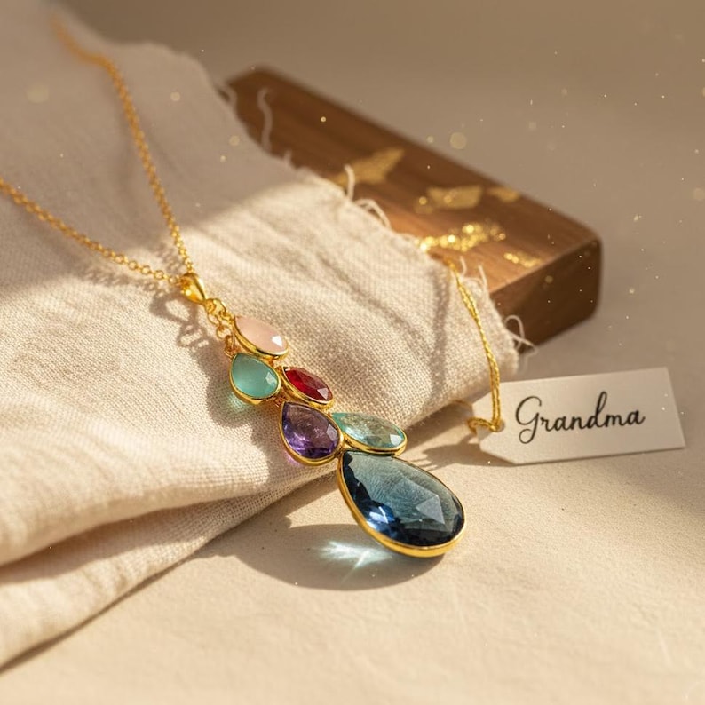 Hand holding a custom birthstone necklace for grandma featuring multiple dangling gemstones, personalized family necklace in gold, birthstone jewelry gift for grandmother