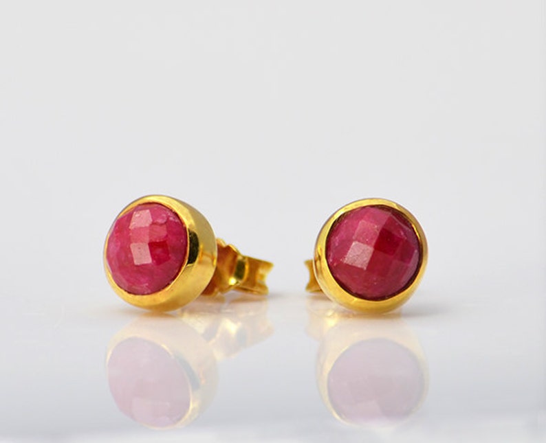 May include: A pair of gold stud earrings with pink ruby gemstones.
