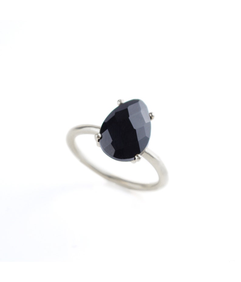 May include: A silver ring with a black gemstone set in a prong setting.