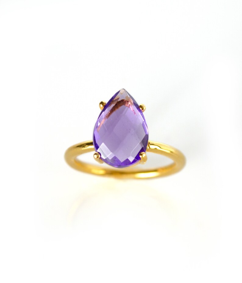 May include: A gold ring with a purple amethyst gemstone in a teardrop shape.