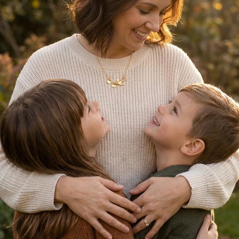 Mother with two children lifestyle shot, family jewelry for mom, personalized initial charms represent each child, sentimental motherhood keepsake necklace.