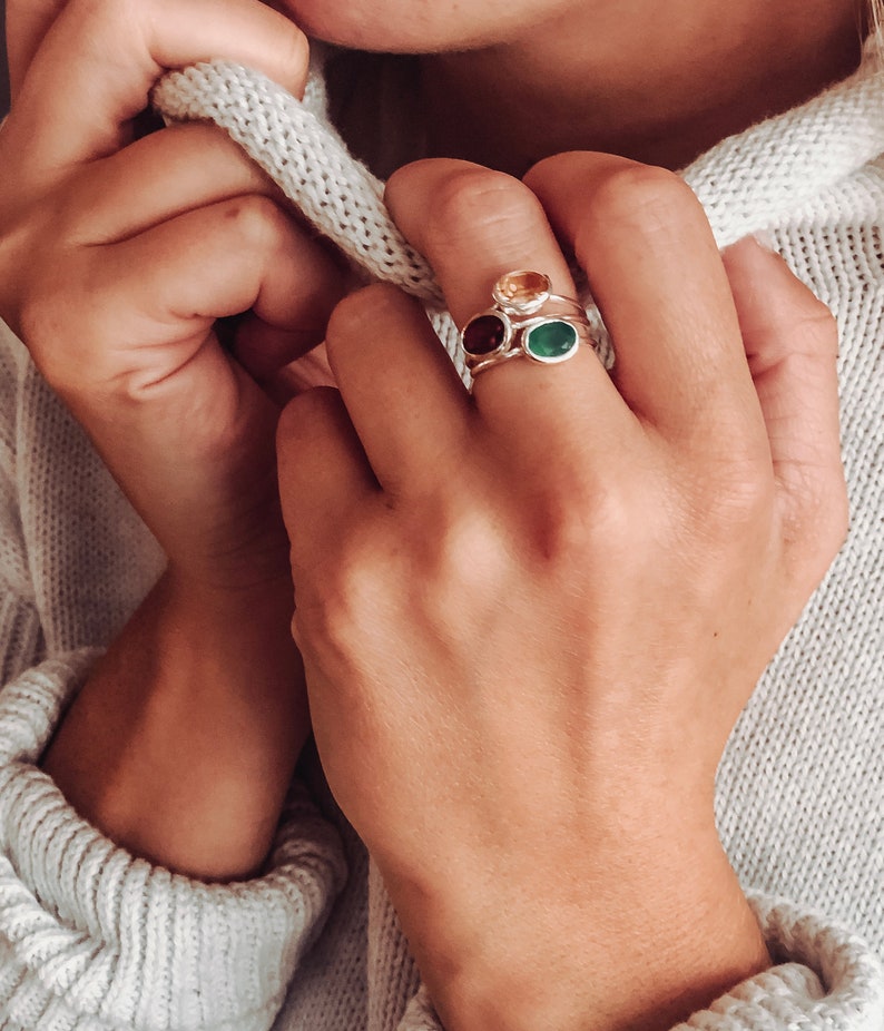 A person wearing a white sweatshirt and a silver gemstone ring set combo. Citrine ring, Garnet ring, Green Onyx ring, silver ring combo set, gold ring combo set, November birthstone ring, January birthstone ring, May birthstone ring, Scorpio jewelry