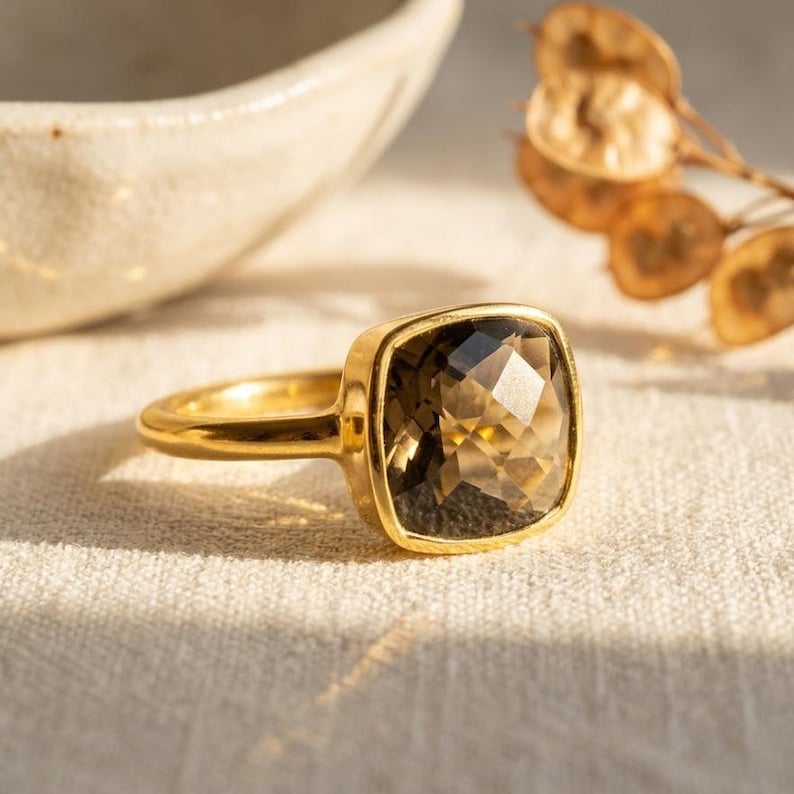 Cushion cut smoky quartz ring in gold bezel setting on neutral background