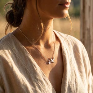 Model wearing sterling silver bird necklace in soft light, minimalist personalized mother’s necklace styling, tiny initial charms for kids or grandkids.