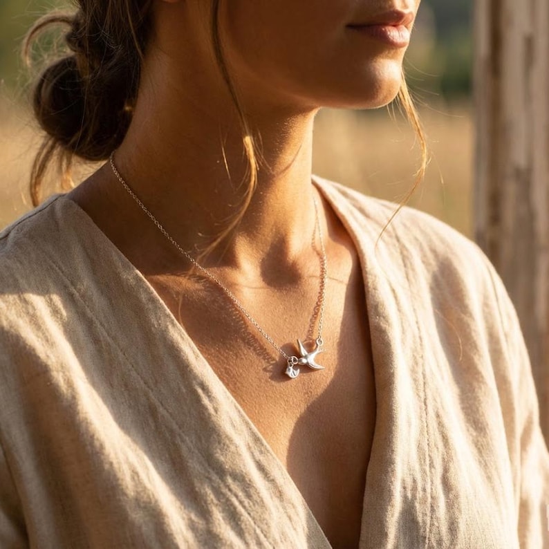 Model wearing sterling silver bird necklace in soft light, minimalist personalized mother’s necklace styling, tiny initial charms for kids or grandkids.