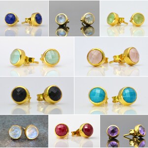 May include: A set of 10 pairs of gold stud earrings with various gemstone colors, including blue, green, pink, black, turquoise, red, and purple.