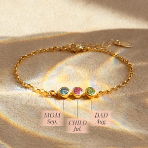 A dainty 3mm birthstone bracelet with mom, dad and child's birthstones set into a bar together.