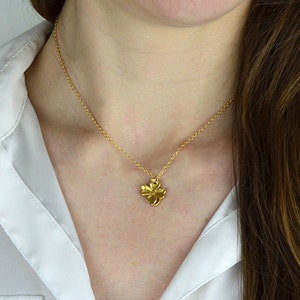 May include: A gold chain necklace with a small, gold, four-leaf clover pendant.