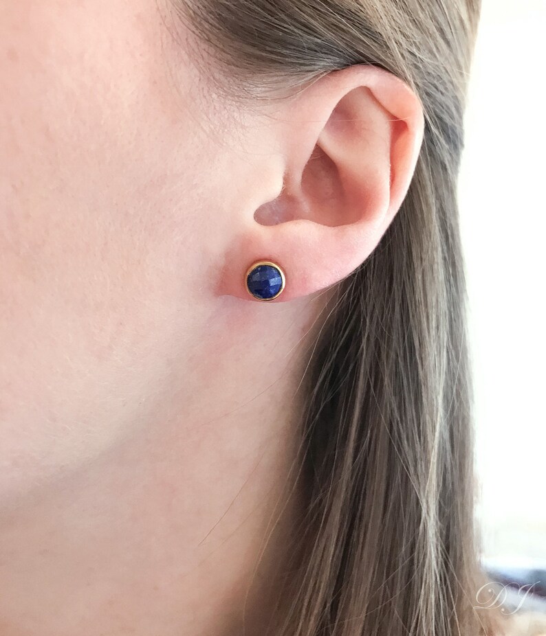 May include: A pair of gold stud earrings with a round blue gemstone.
