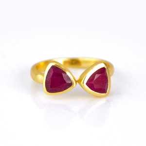 May include: A gold ring with two triangular ruby stones set in the band.