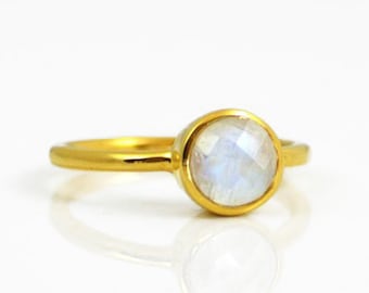 May include: A gold ring with a round, white moonstone gemstone.