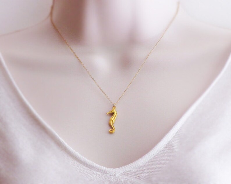 May include: A gold necklace with a seahorse pendant. The seahorse is detailed and has a textured surface.
