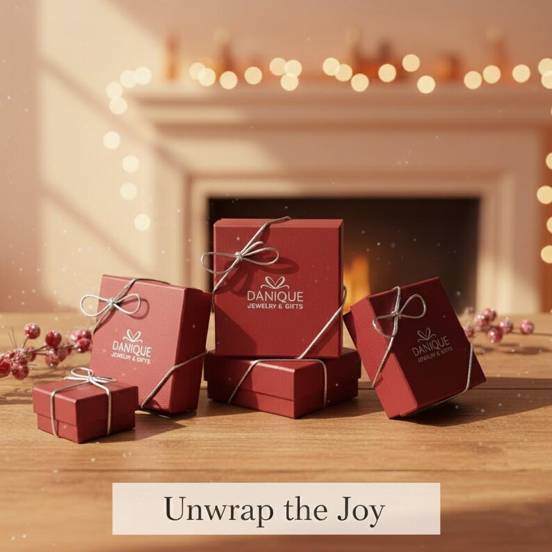 Holiday scene with Danique Jewelry red gift boxes, gold ornaments, and frosted greenery on soft ivory fabric. Festive packaging photo for personalized necklaces, rings, and bracelets—thoughtful Christmas gift for mom, wife, or girlfriend.