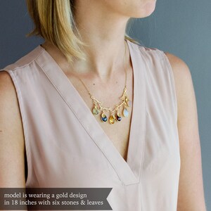 May include: A gold necklace with a branch design and six colorful gemstone drops. The necklace is 18 inches long.
