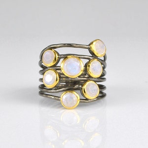 May include: A silver ring with multiple bands and moonstone gemstones set in gold.