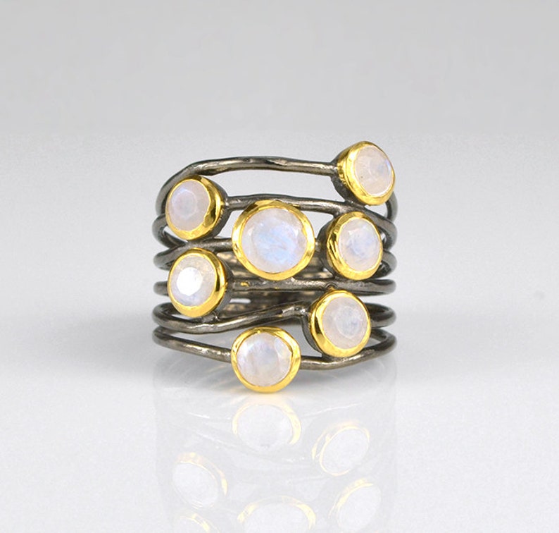 May include: A silver ring with multiple bands and moonstone gemstones set in gold.