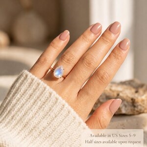 Moonstone teardrop ring worn on hand with text overlay showing available US sizes 5 to 9 and half sizes available upon request. A helpful sizing image for a June birthstone ring, pear gemstone ring, rainbow moonstone ring, and gift for her.