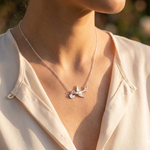Model wearing the bird family necklace, delicate everyday layering look, personalized initial charm necklace for mom, minimalist mother’s necklace in sterling silver tone.