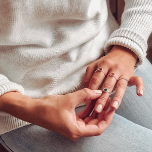 A person wearing a white sweatshirt and a silver gemstone ring set combo. Birthstone ring set, birthstone rings, gemstone rings, zodiac rings, silver crystal jewelry, gold crystal jewelry, protection stones, happiness stones, crystals for connection