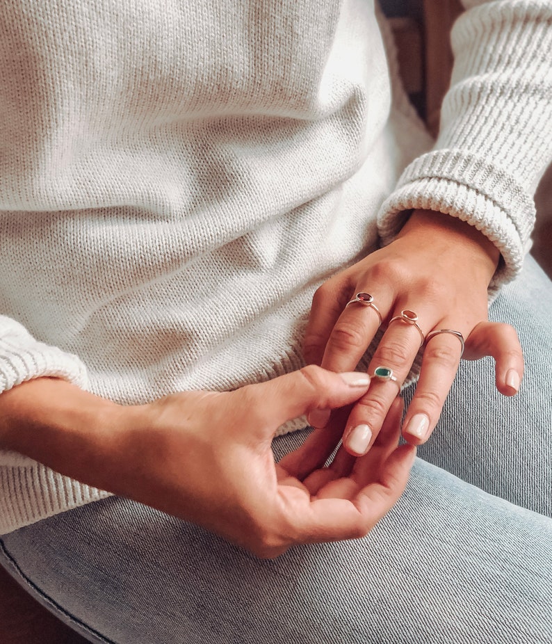 A person wearing a white sweatshirt and a silver gemstone ring set combo. Birthstone ring set, birthstone rings, gemstone rings, zodiac rings, silver crystal jewelry, gold crystal jewelry, protection stones, happiness stones, crystals for connection