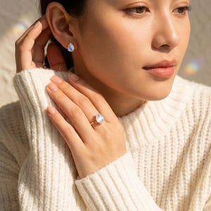 Model wearing matching moonstone ring and moonstone stud earrings in warm sunlight, showing coordinated June birthstone jewelry. A rainbow moonstone ring and earring set idea for birthdays, bridesmaids, Mother’s Day, anniversary gifts, and gemstone jewelry lovers.