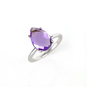 May include: A silver ring with a large, pear-shaped amethyst gemstone.