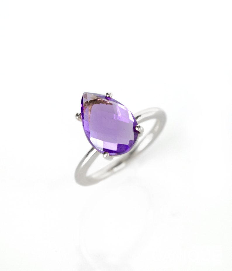 May include: A silver ring with a large, pear-shaped amethyst gemstone.