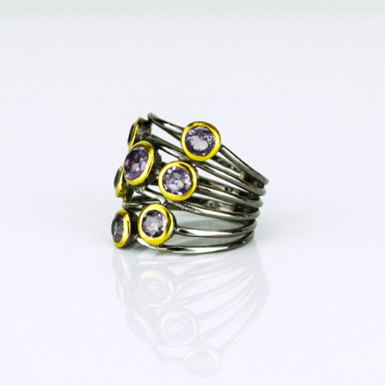 May include: A silver ring with multiple bands and purple gemstones set in yellow gold.