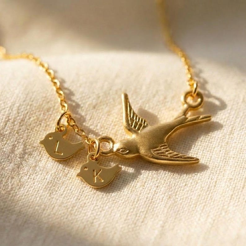 Close-up of gold mama bird pendant with baby bird initial discs, custom family necklace detail shot, sweet gift for new mom, baby shower or Mother’s Day.