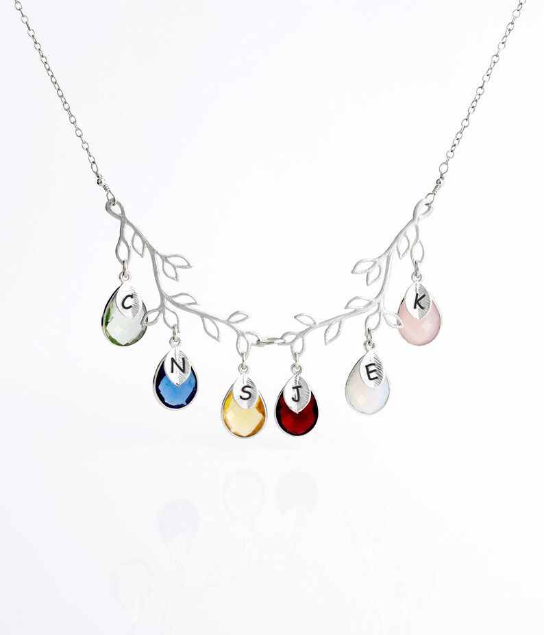 May include: Silver necklace with a branch design and six teardrop-shaped crystals. Each crystal has a letter engraved on it: C, N, S, J, E, and K.