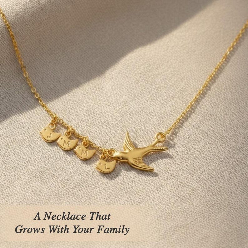 Gold necklace flatlay with text overlay, mama bird and baby bird initials, “growing with your family” concept for an expandable family charm necklace.