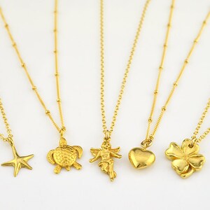 May include: Five gold necklaces with different charms. The charms include a starfish, a turtle, an angel, a heart, and a four-leaf clover.