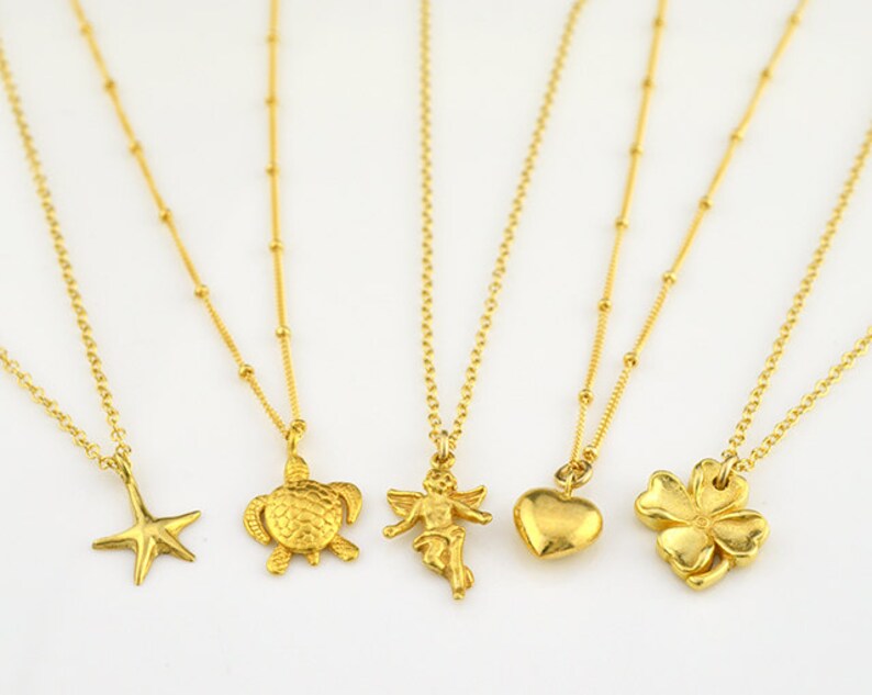 May include: Five gold necklaces with different charms. The charms include a starfish, a turtle, an angel, a heart, and a four-leaf clover.