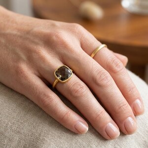 Cushion cut smoky quartz ring in gold on white background, minimalist bezel set gemstone ring