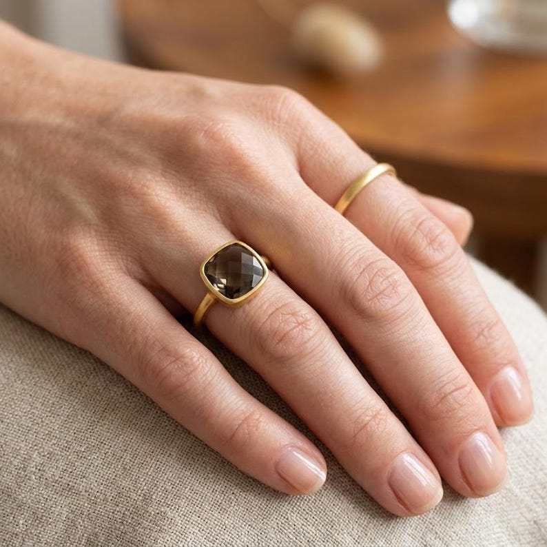 Cushion cut smoky quartz ring in gold on white background, minimalist bezel set gemstone ring