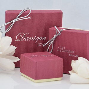 May include: Three red gift boxes with silver ribbon and the text "Dannique Jewelry" printed on the front.