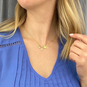 Gold necklace flatlay with chain and mama bird charm, elegant personalized initial charm necklace, meaningful Mother’s Day or anniversary gift.