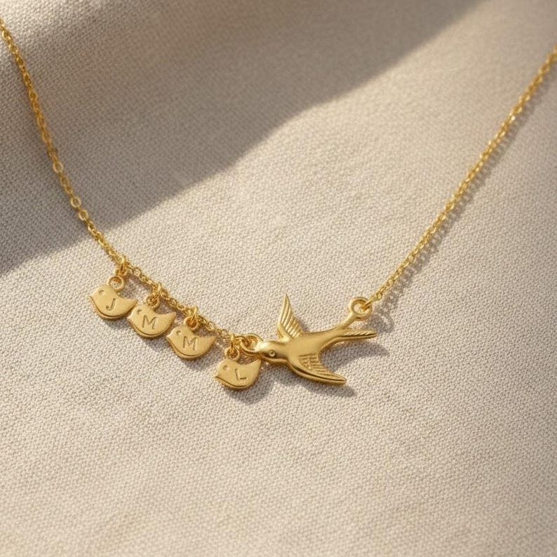 Model in blue top wearing gold mama bird necklace, everyday fashion styling for personalized family jewelry, initial baby bird charms as a keepsake.