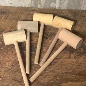 May include: Five wooden mallets with light brown handles and different colored heads. The heads are light brown, dark brown, and beige.